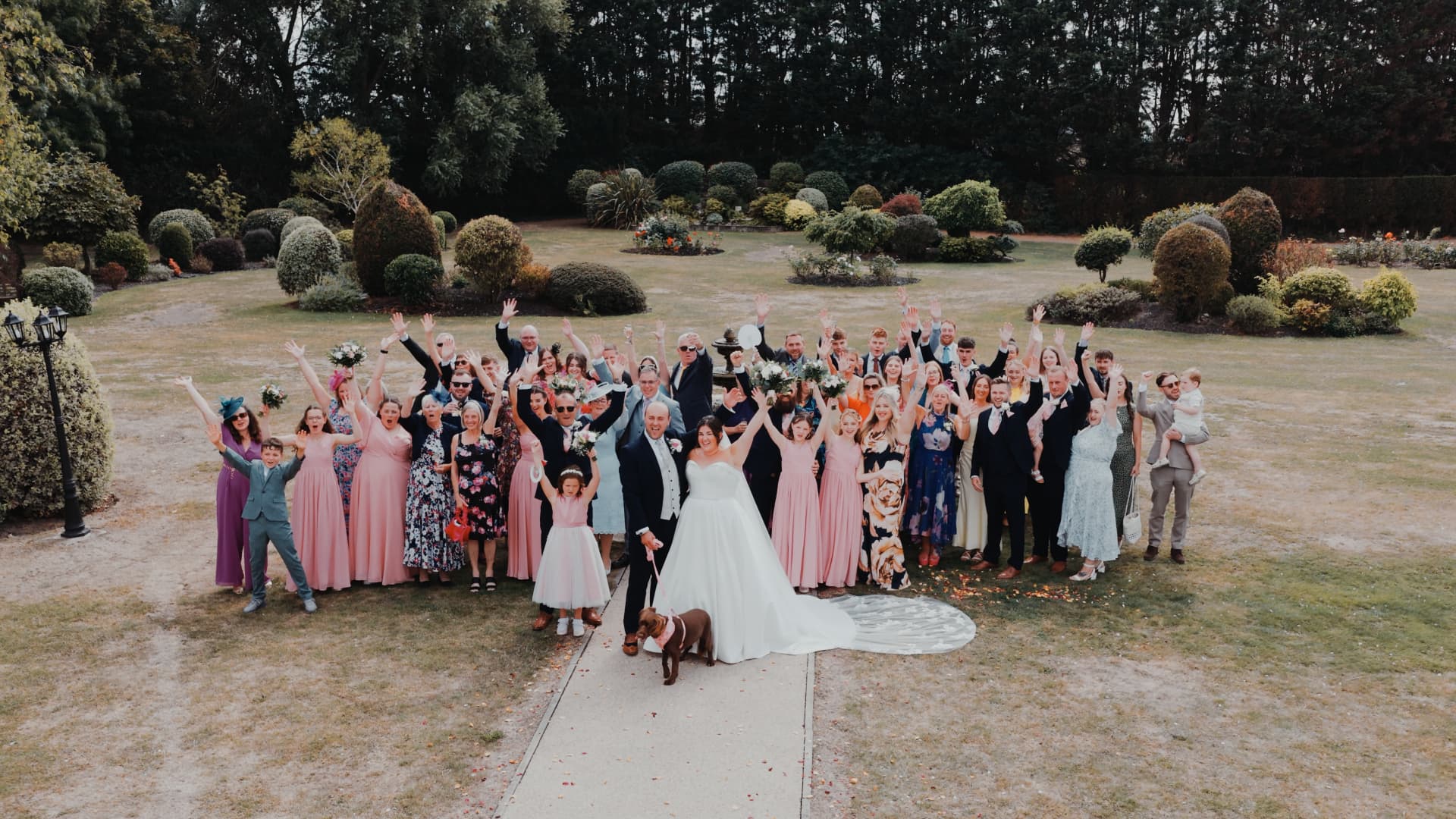Drone wedding videography capturing the couple with family and friends at Batch Country House, surrounded by beautiful Somerset gardens and golden fields.