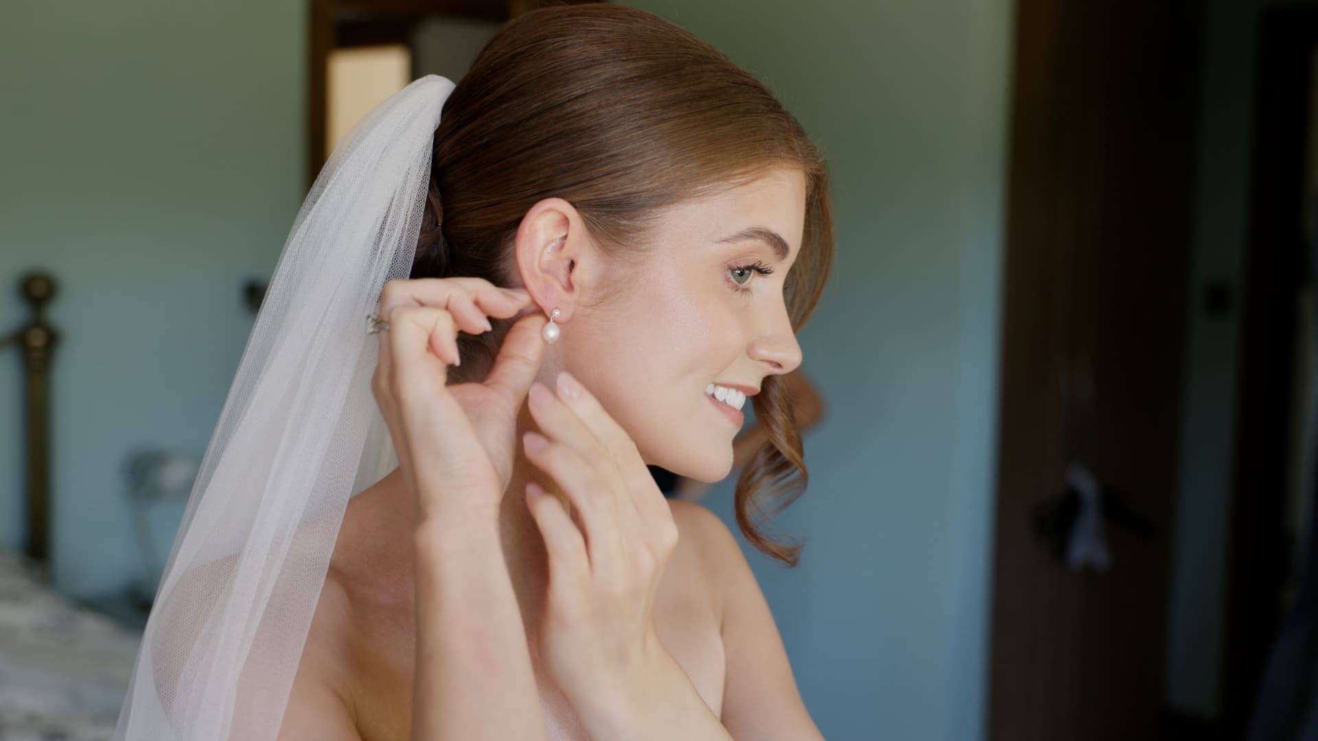 Bride putting on her earrings during morning preparations, captured by a Somerset wedding videographer.