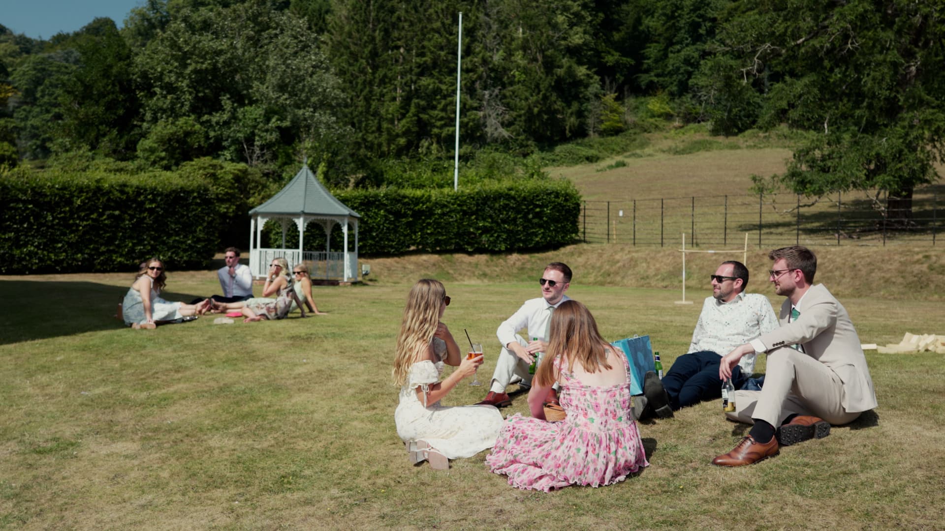 Wedding guests enjoying drinks and sunshine on the lawn during a relaxed sunny celebration in Somerset.