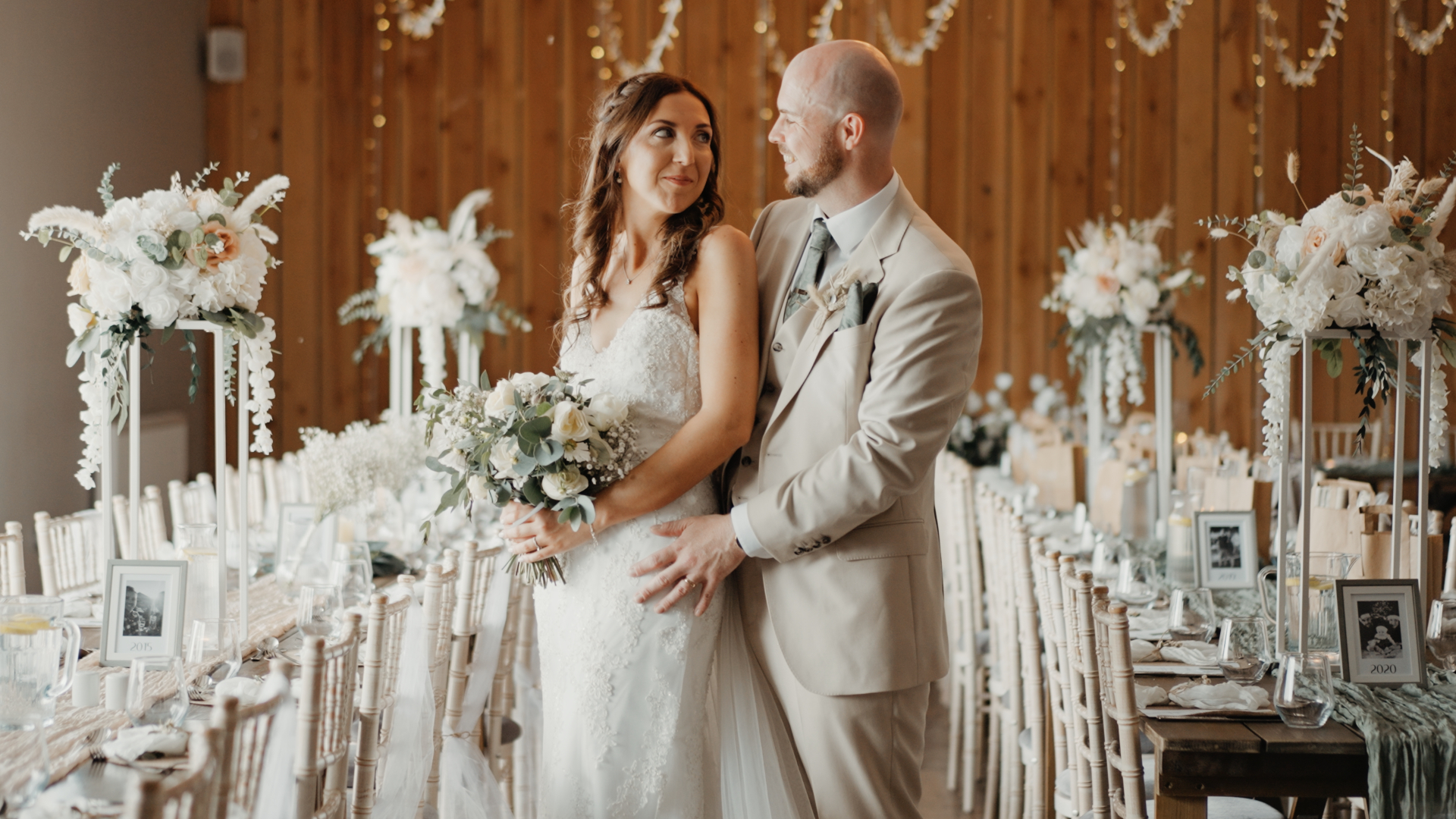 Newlyweds standing together inside Humber Barn, surrounded by elegant rustic décor, floral centrepieces, and soft golden lighting.