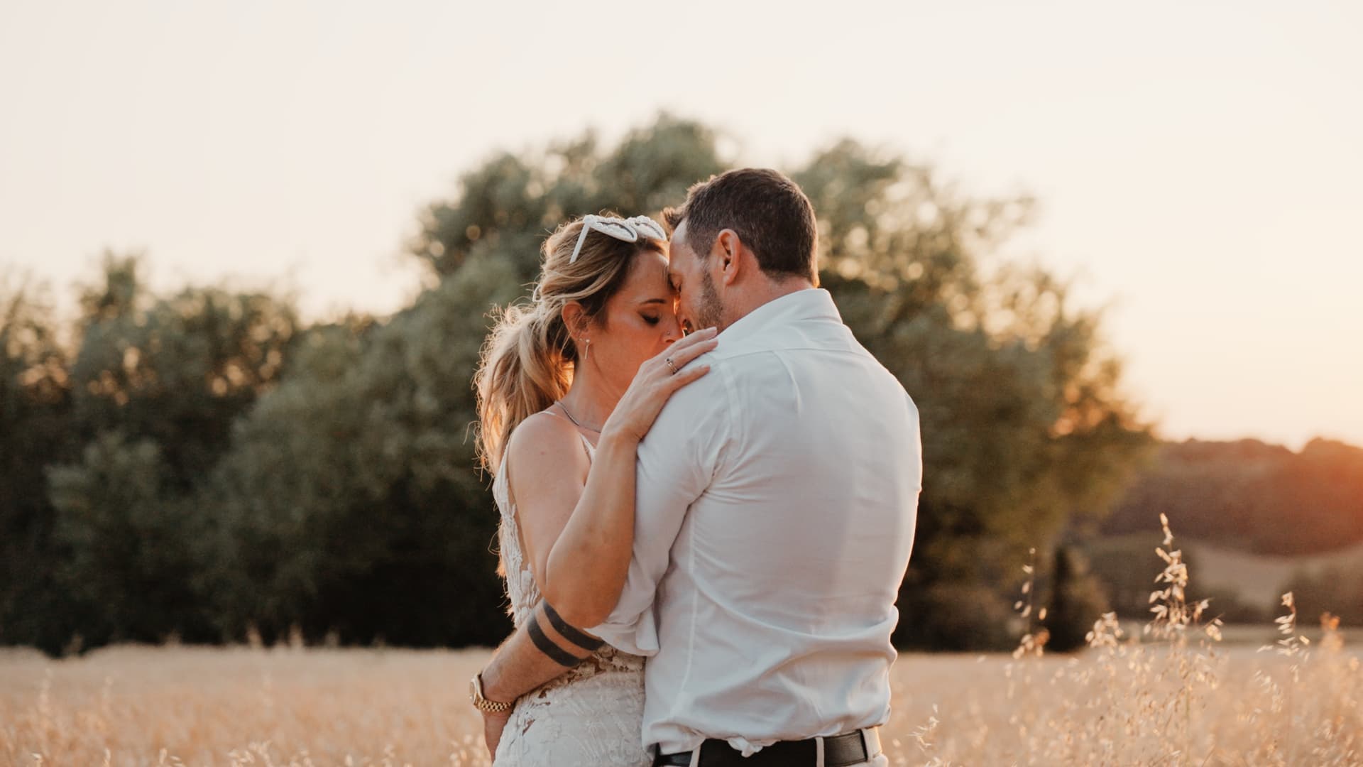 Bride and groom embrace in a golden Somerset field at sunset.