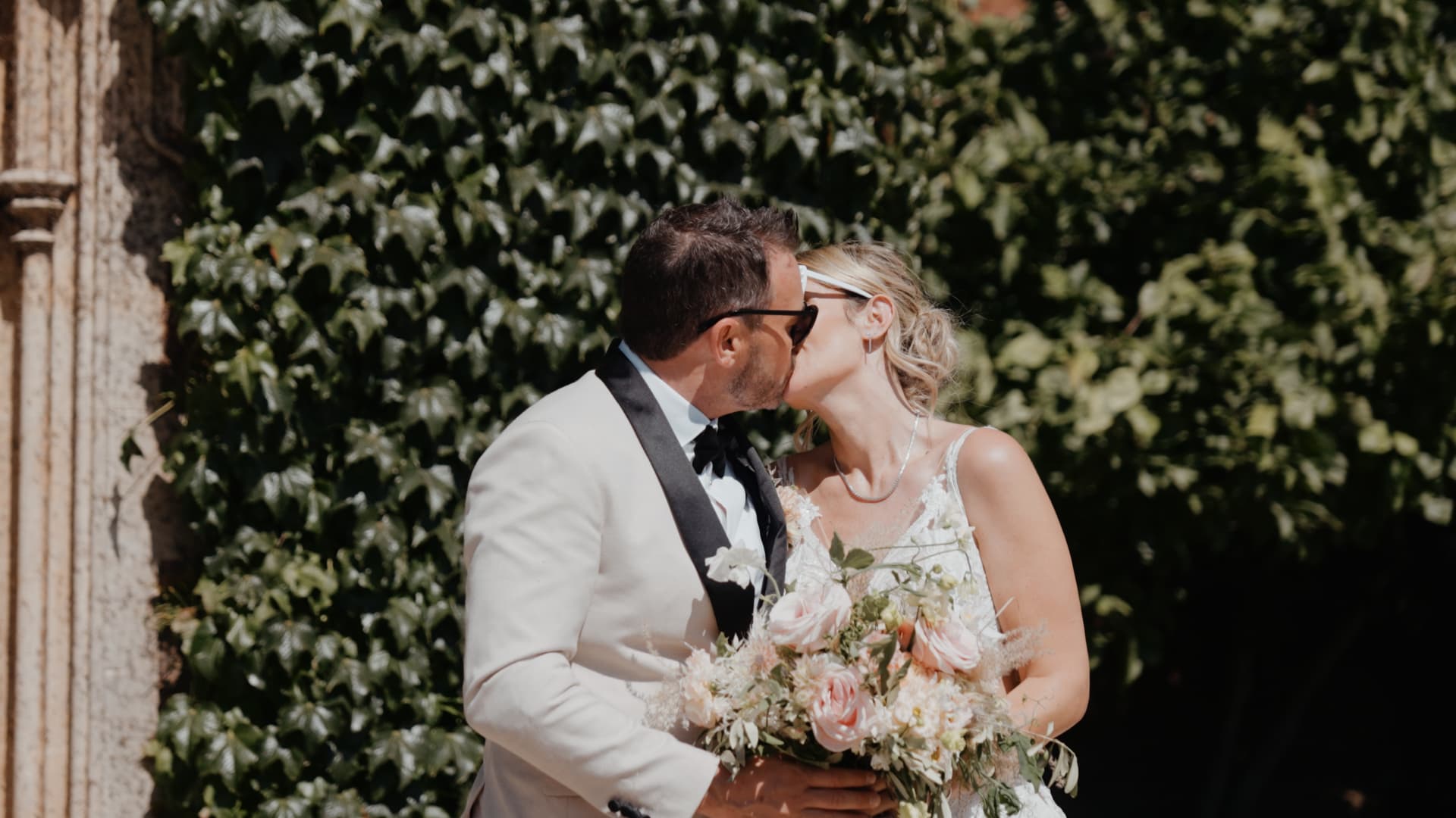 Bride and groom share a romantic golden hour kiss outside St Audries Park, surrounded by soft sunlight and summer greenery.