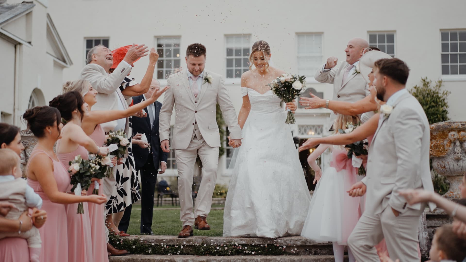 Bride and groom walk hand in hand through a joyful confetti shower surrounded by loved ones at their fall wedding.