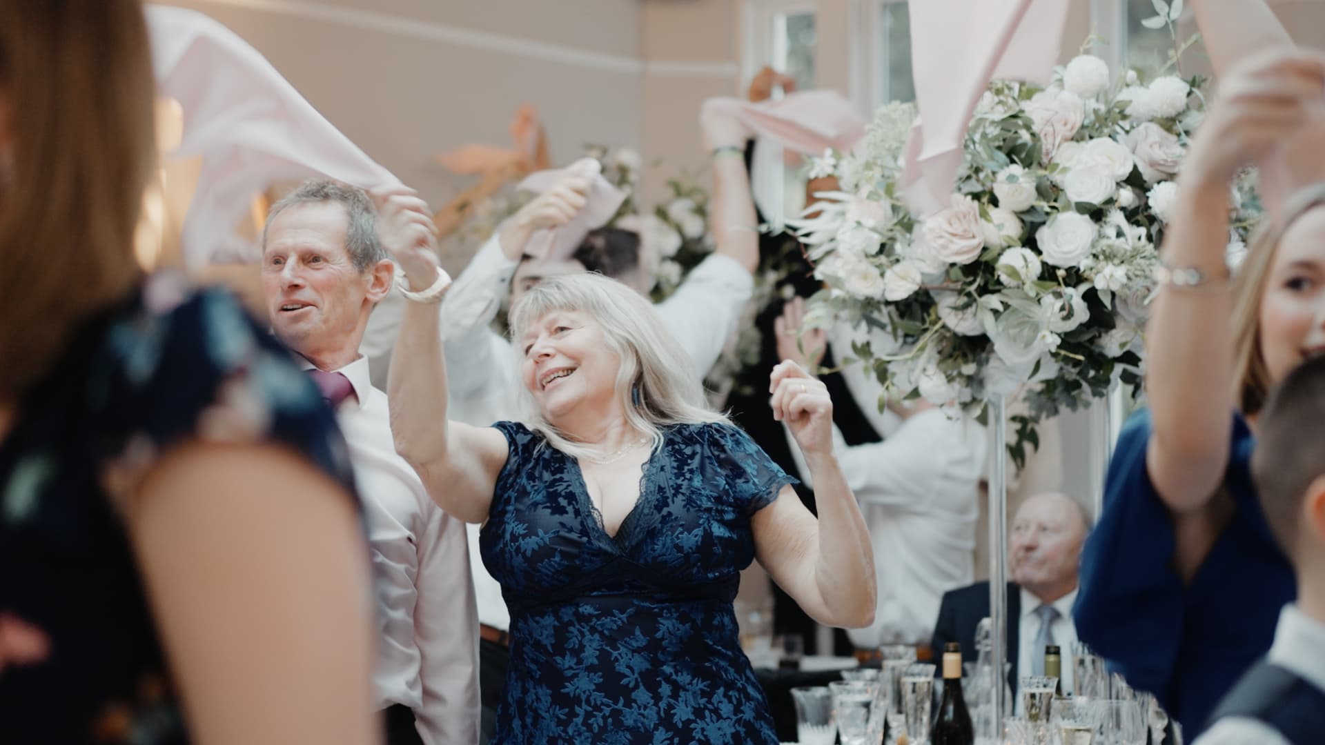 Guests wave napkins and dance joyfully during the evening reception at Rockbeare Manor, capturing pure happiness.