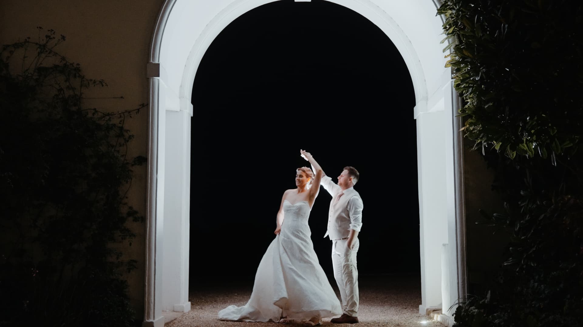 Newlyweds enjoy their first dance under the glowing archway at Rockbeare Manor during their elegant evening celebration.