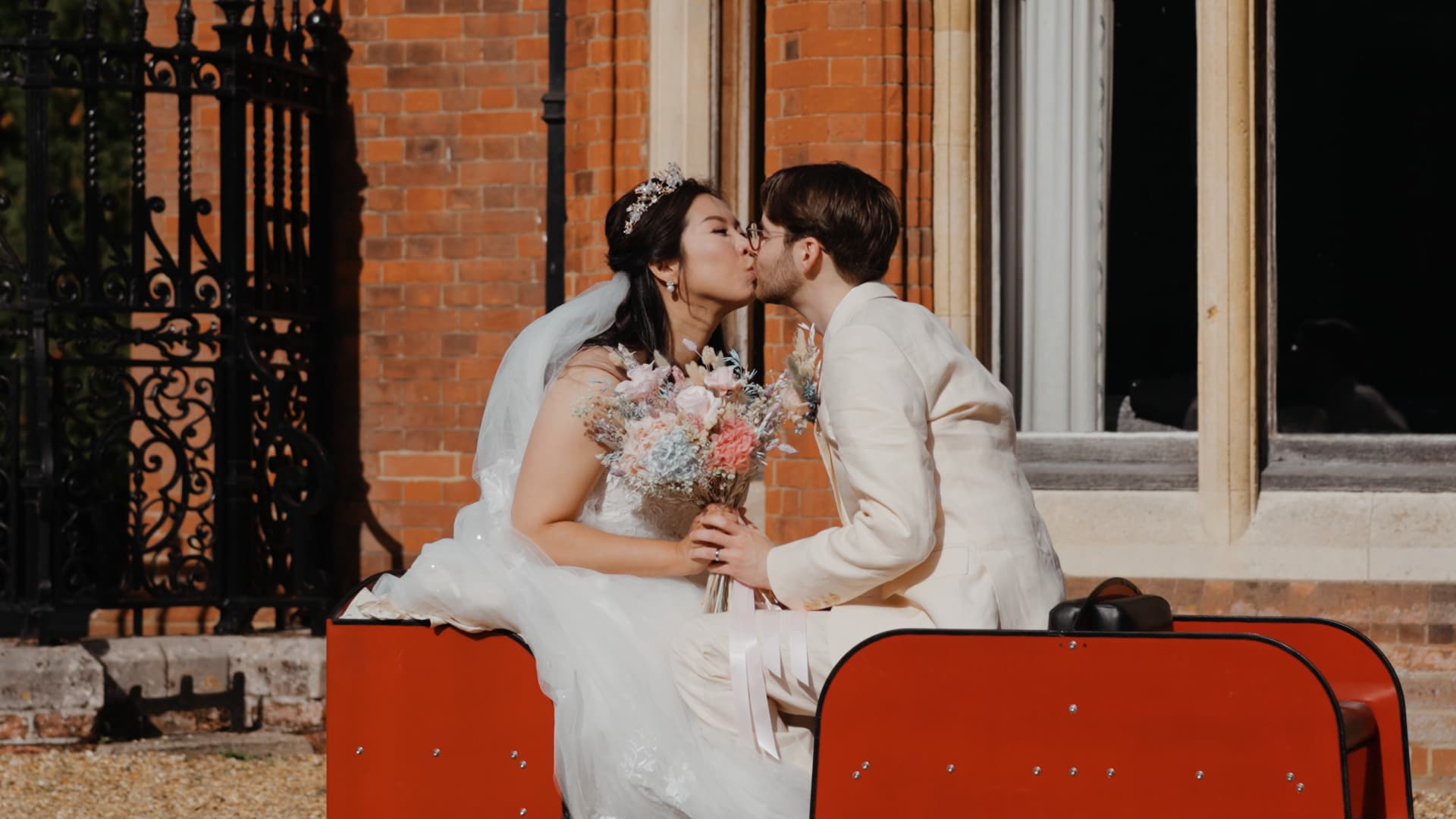 Tender moment of the couple sharing a kiss on the miniature railway cart, beautifully captured for their wedding film.