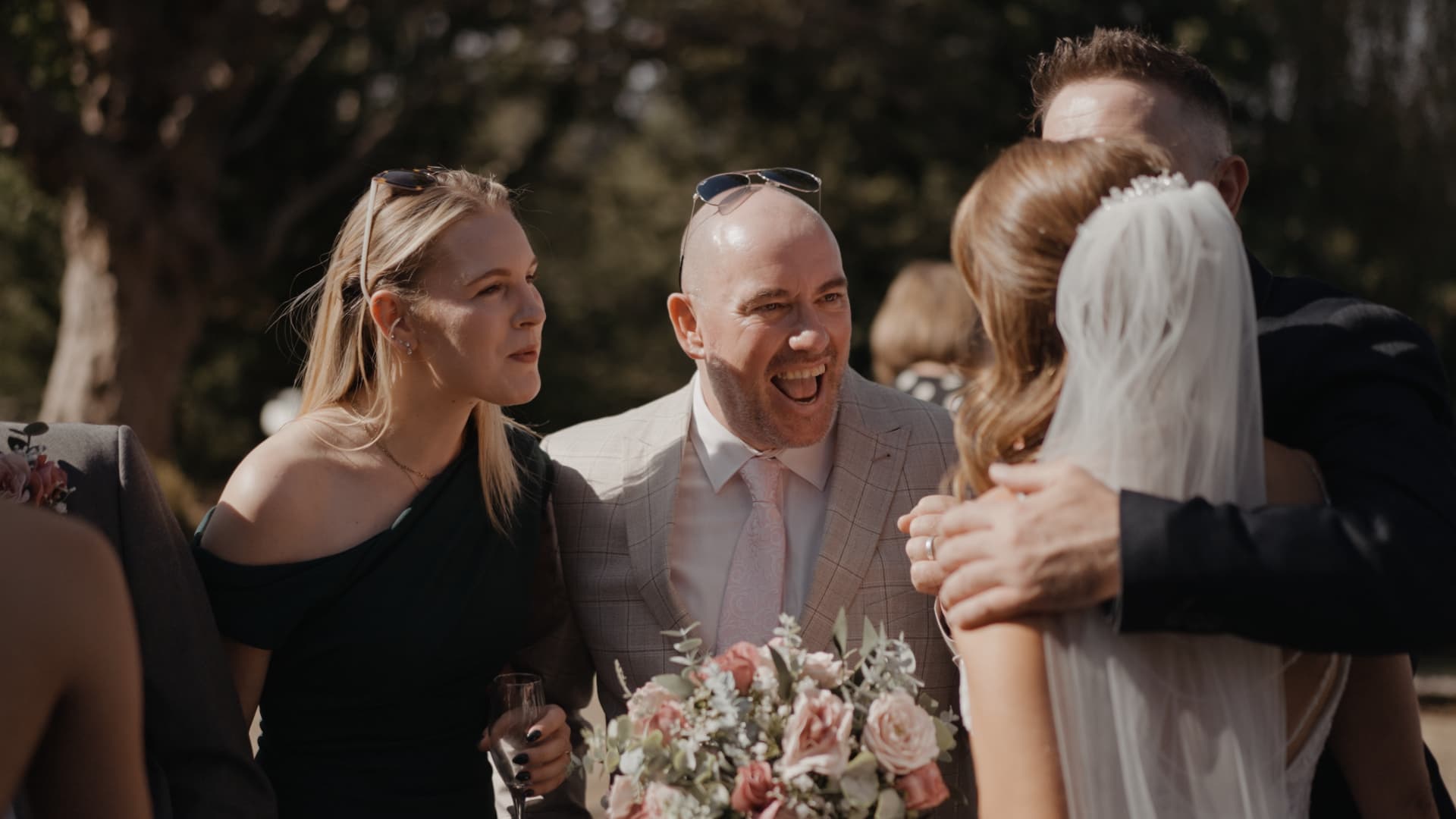 Guests sharing joyful moments outdoors captured by a wedding videographer.