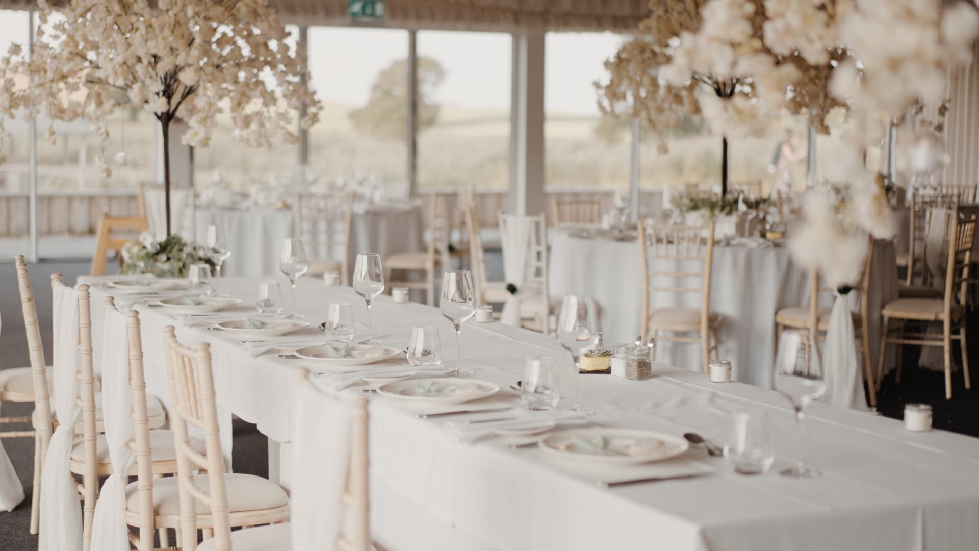 Elegant white wedding tablescape with blossom centrepieces and soft neutral décor inside the barn at Quantock Lakes Wedding Venue.