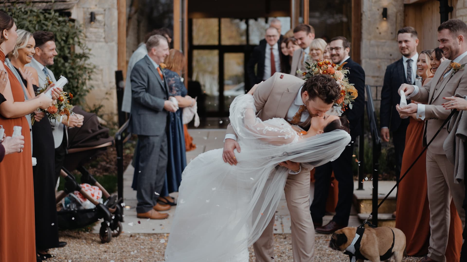 Bride and groom sharing a dip kiss during confetti exit at Great Tythe Barn, captured by a wedding videographer