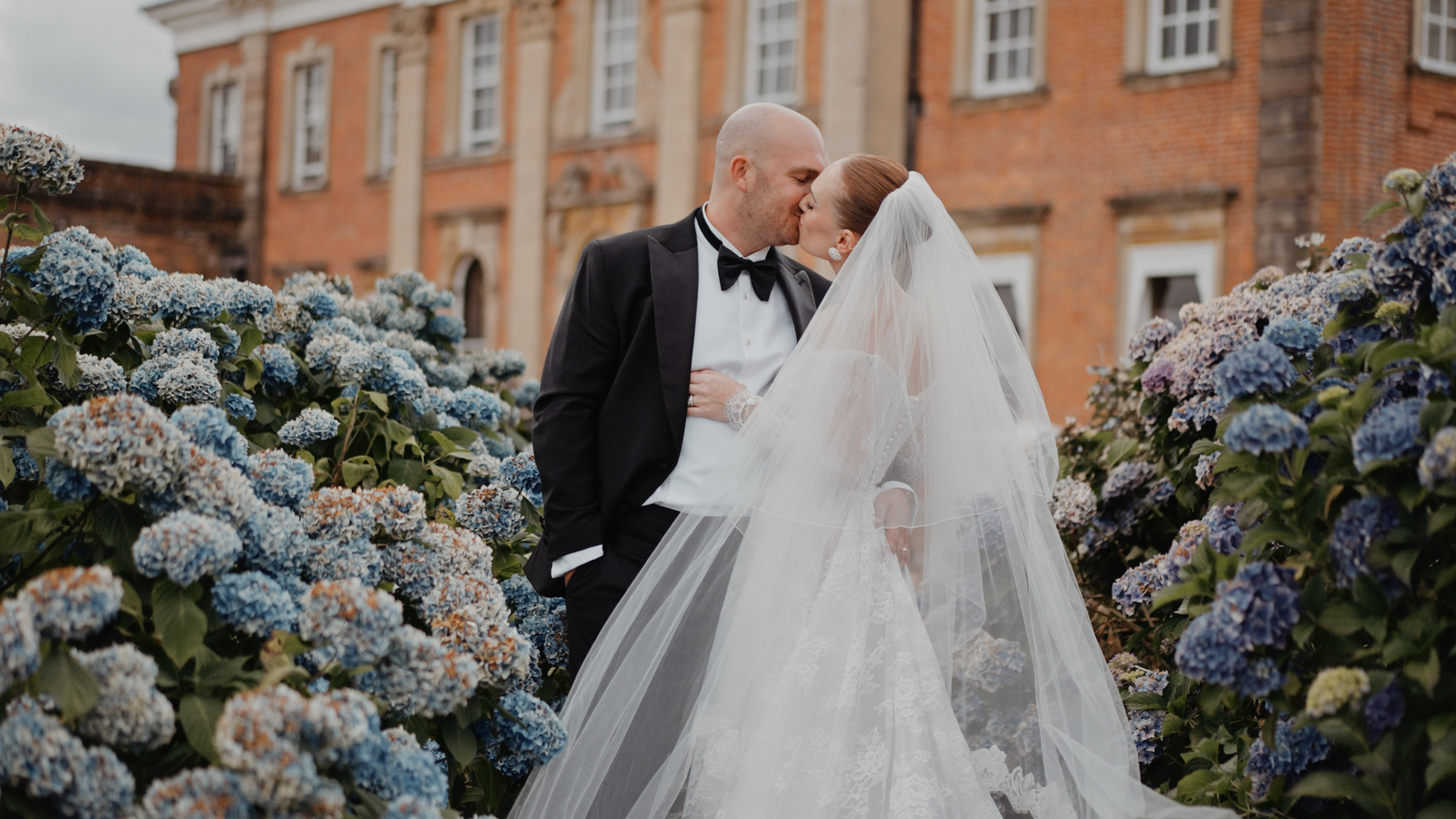 Bride and groom kissing in hydrangea gardens at Crowcombe Court, captured in natural wedding videography style