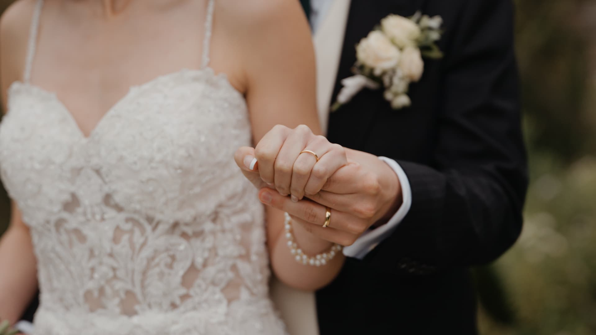 Close-up of couple holding hands and showing wedding rings at Orchardleigh Estate, Somerset, captured in natural documentary style wedding videography with a luxury visual finish