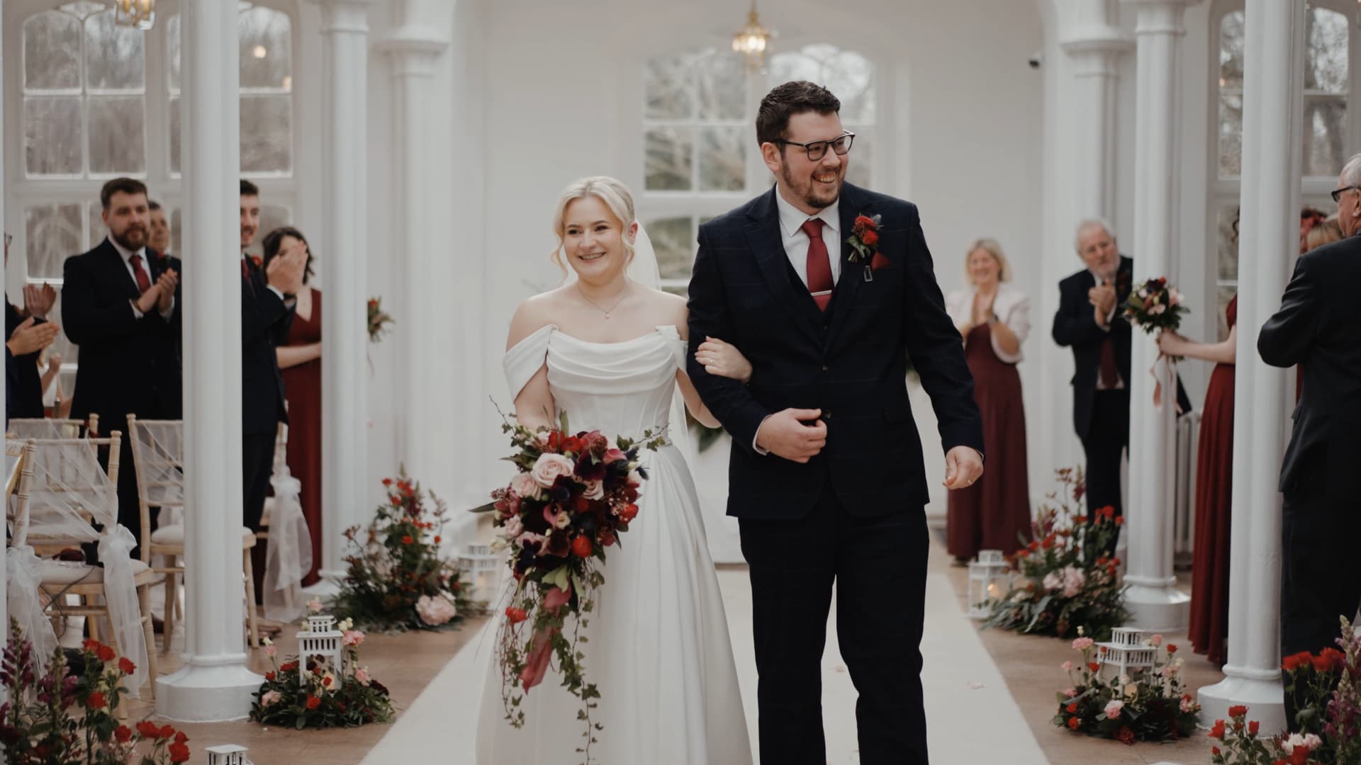 Bride and groom walking down the aisle after ceremony at a St Audries Park wedding orangery with guests celebrating