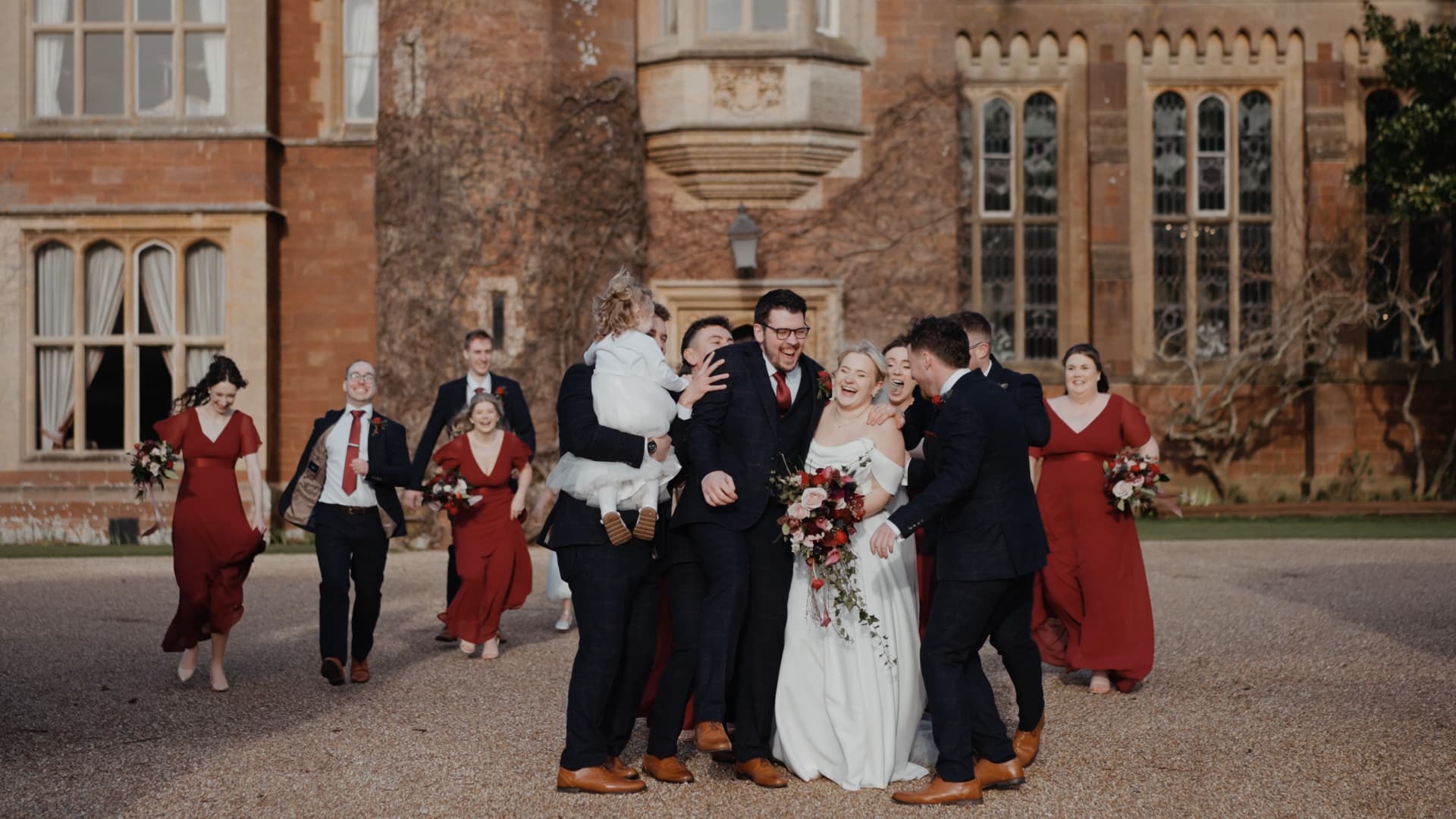 Fun wedding party group shot outside St Audries Park manor captured by a Somerset wedding videographer with joyful candid energy