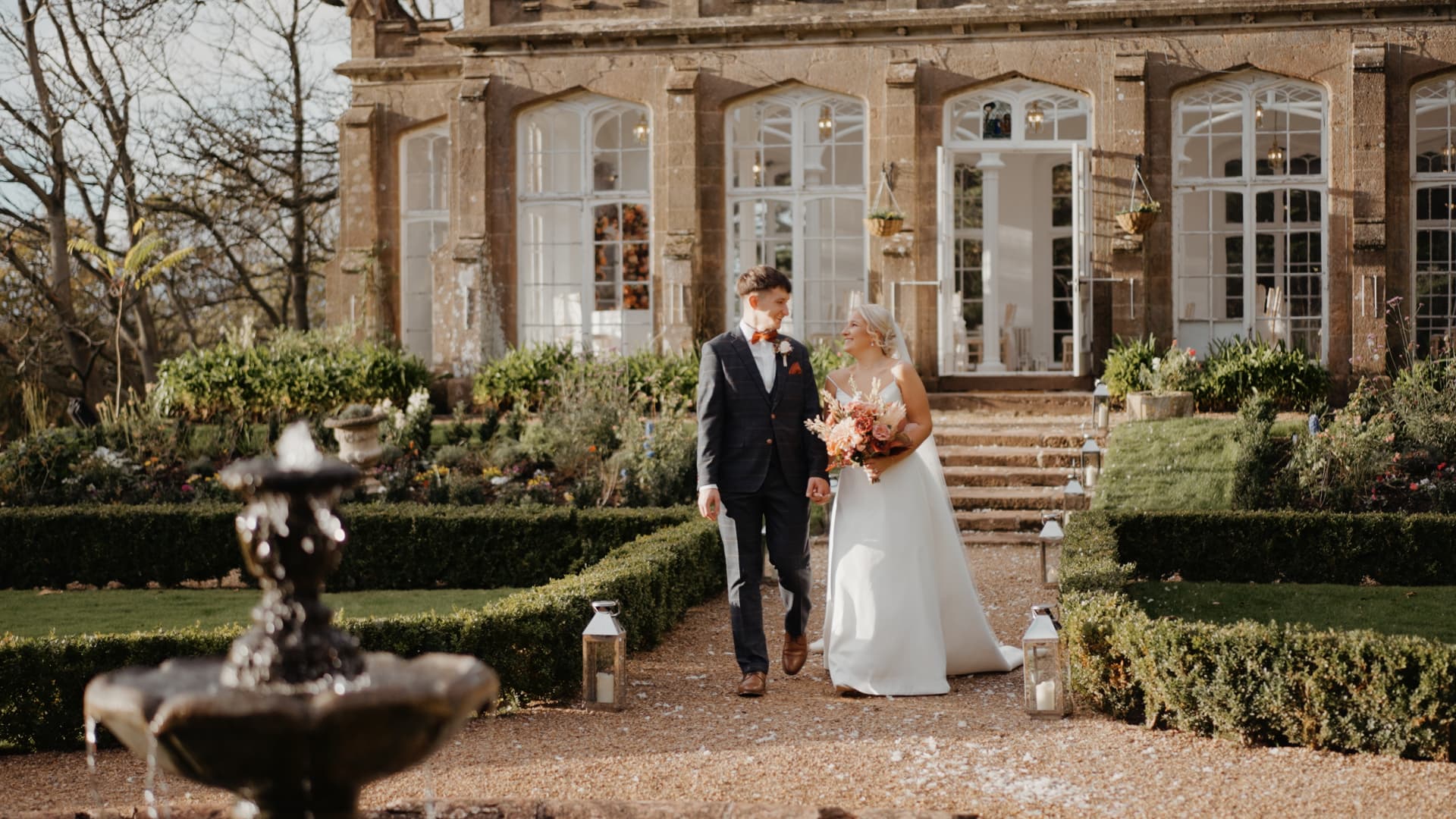 Couple walking through gardens at St Audries Park in Somerset, captured naturally by a Somerset wedding videographer in a cinematic wedding film style