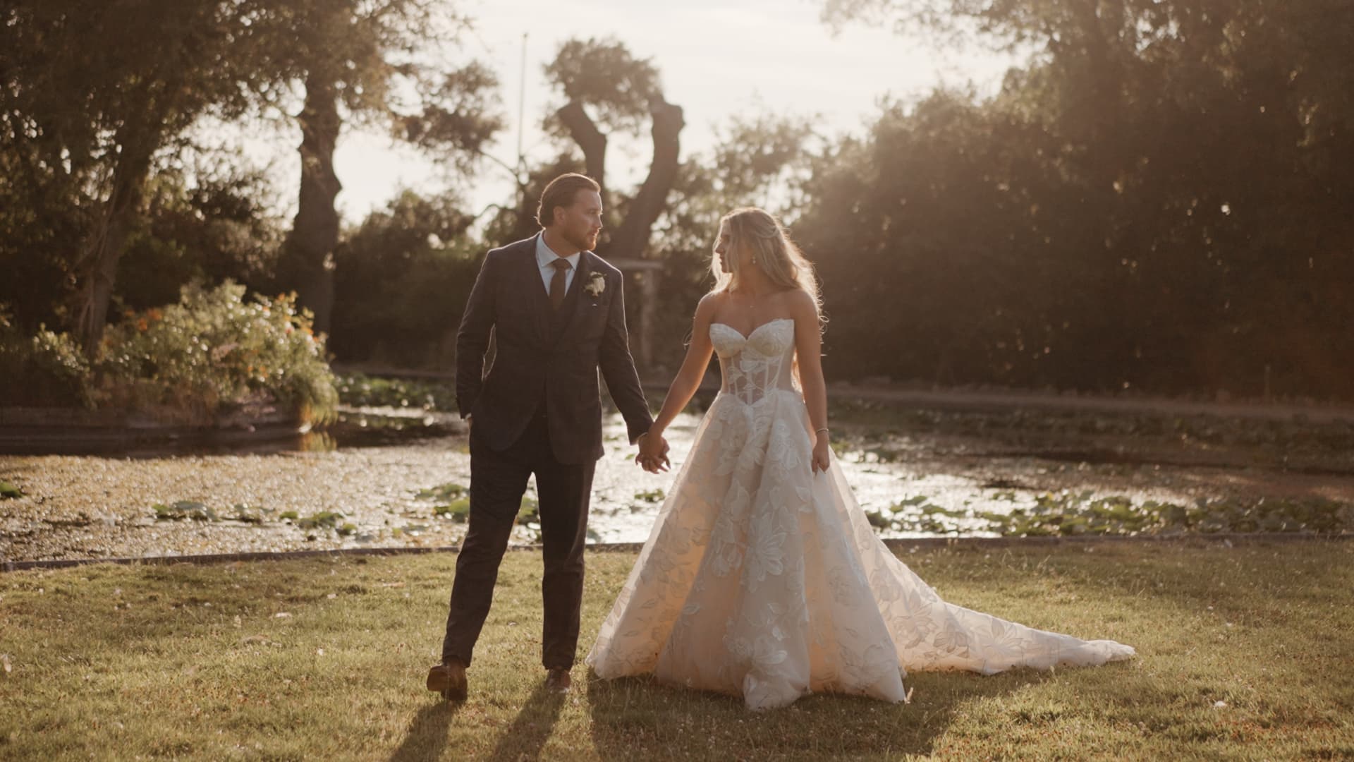 Bride and groom walking by the lake at Clevedon Hall in Somerset during golden hour, captured in a UK wedding videography cinematic wedding film