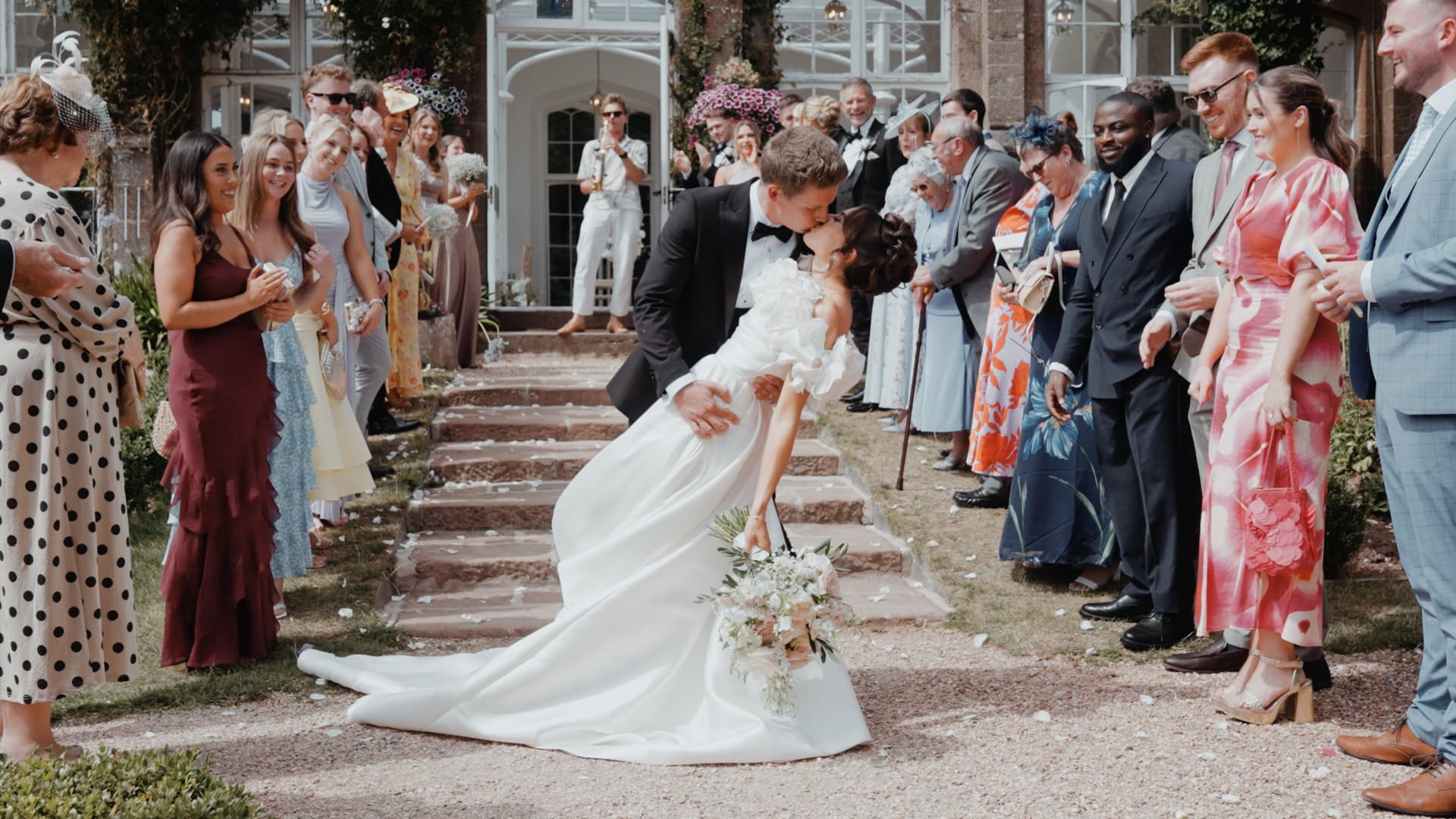 Newlyweds sharing a dip kiss during confetti at St Audries Park, Somerset, captured in a cinematic documentary wedding film