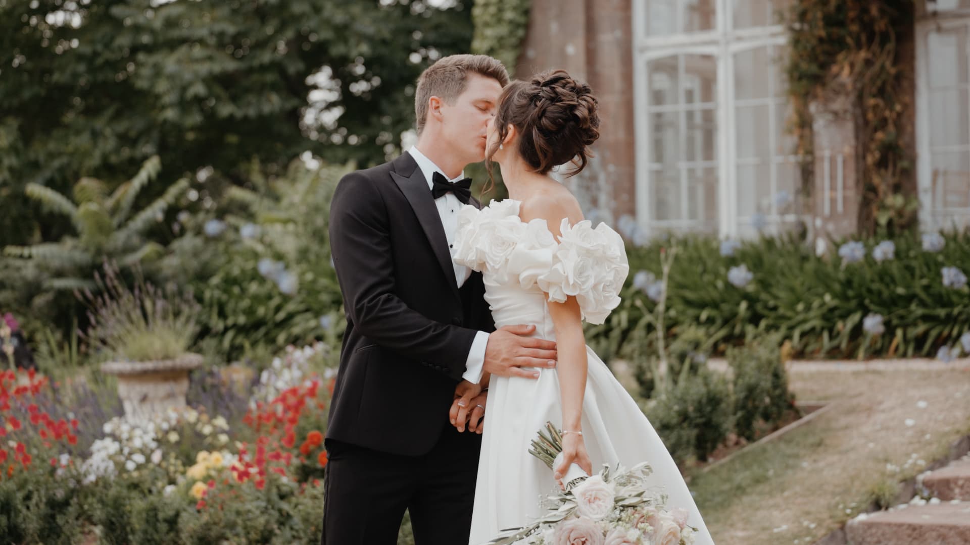Bride and groom sharing a kiss in the gardens at St Audries Park, Somerset, captured by a Somerset based wedding videographer in a cinematic wedding film style