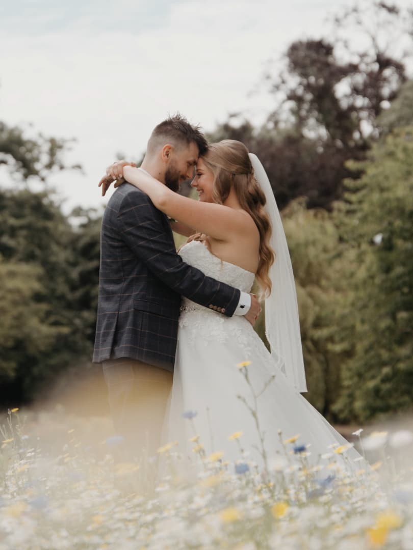 Bride and groom embracing in a wildflower meadow at Clevedon Hall, Somerset, captured by a Somerset based wedding videographer in a luxury documentary wedding film style