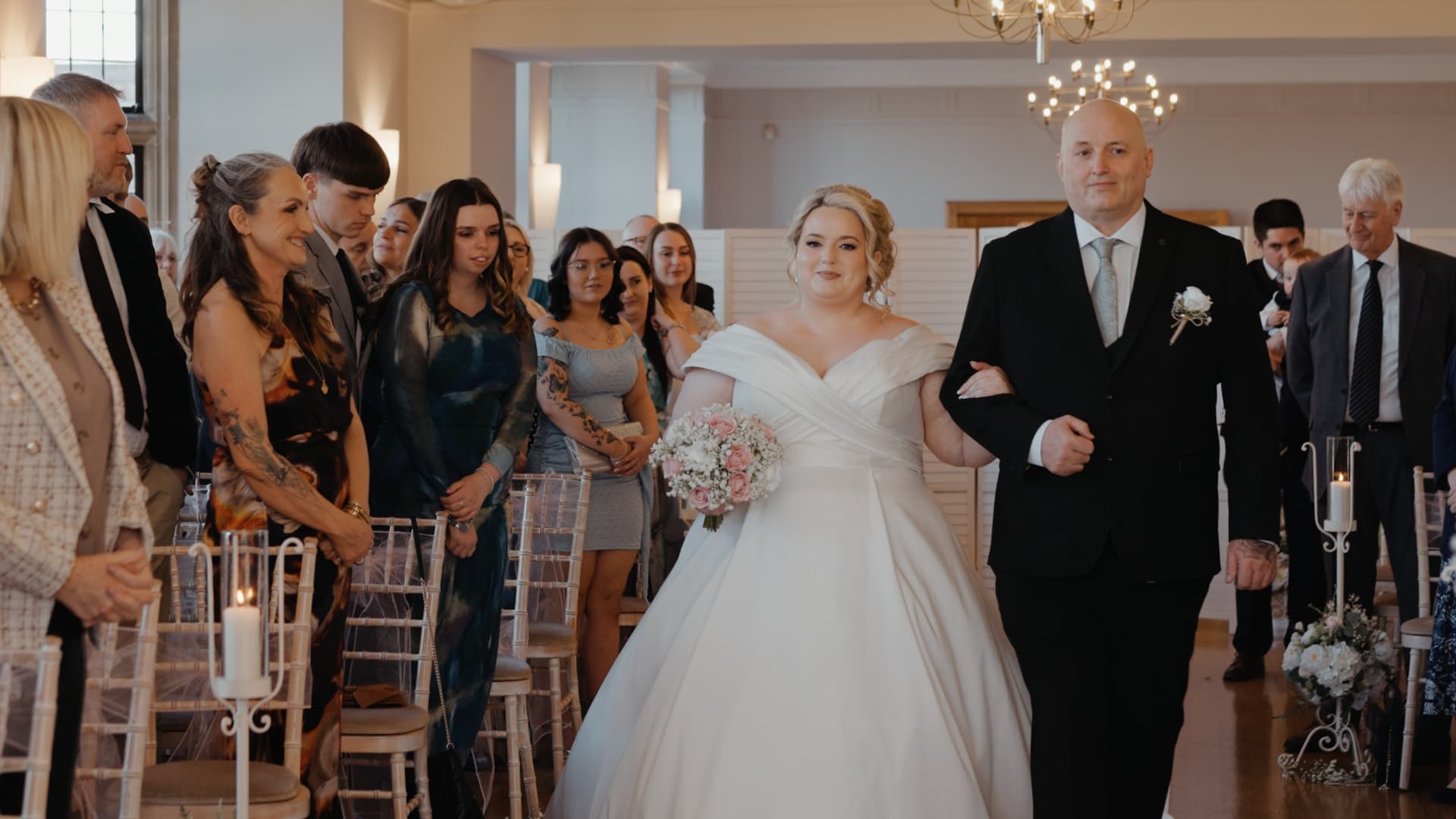 Emotional bride walking down the aisle with her father at Coombe Lodge Blagdon while guests watch with excitement and anticipation during their wedding ceremony.