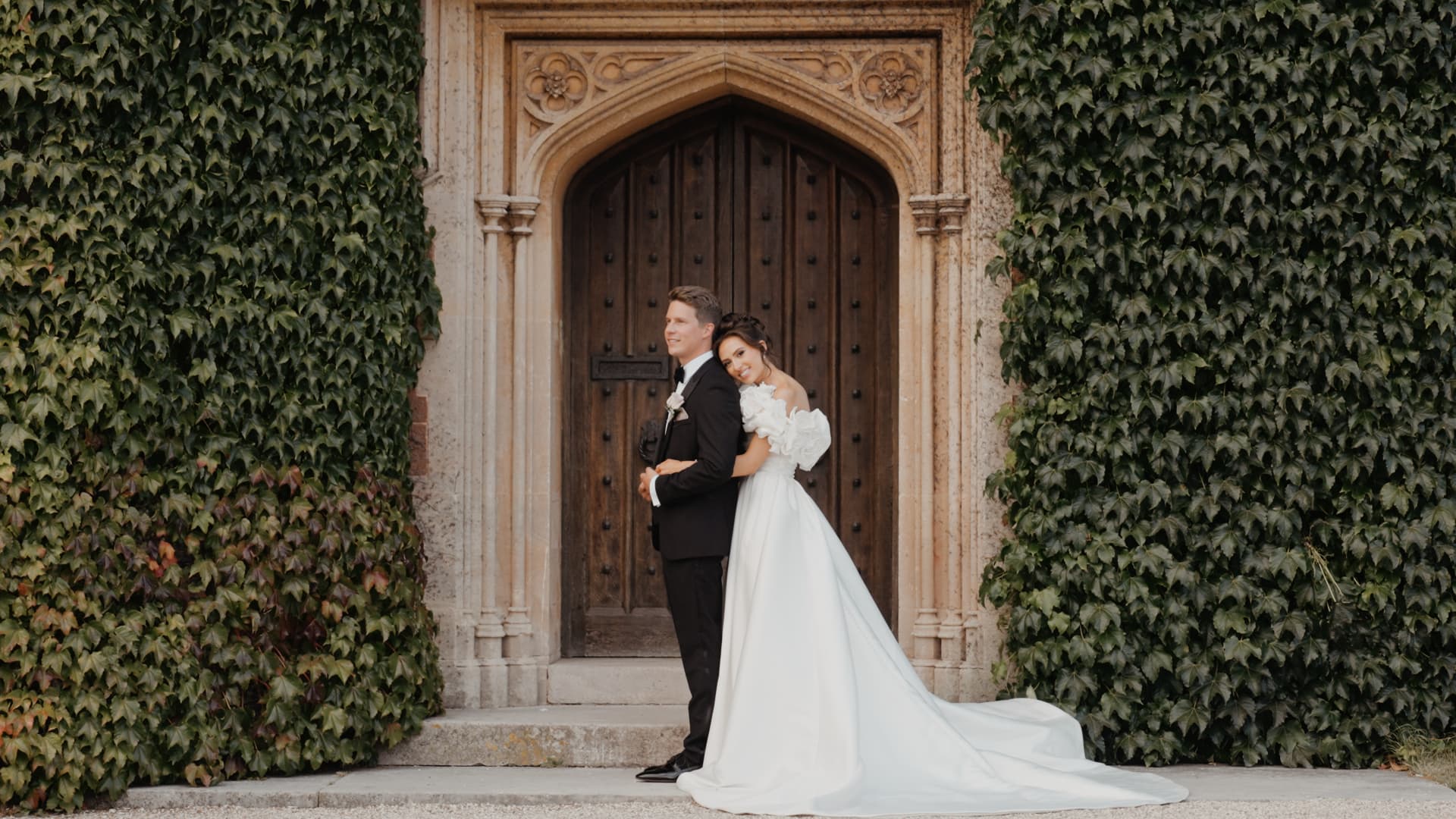 Bride and groom pose against an ivy-covered wall, capturing timeless portraits with a touch of fun wedding ideas.