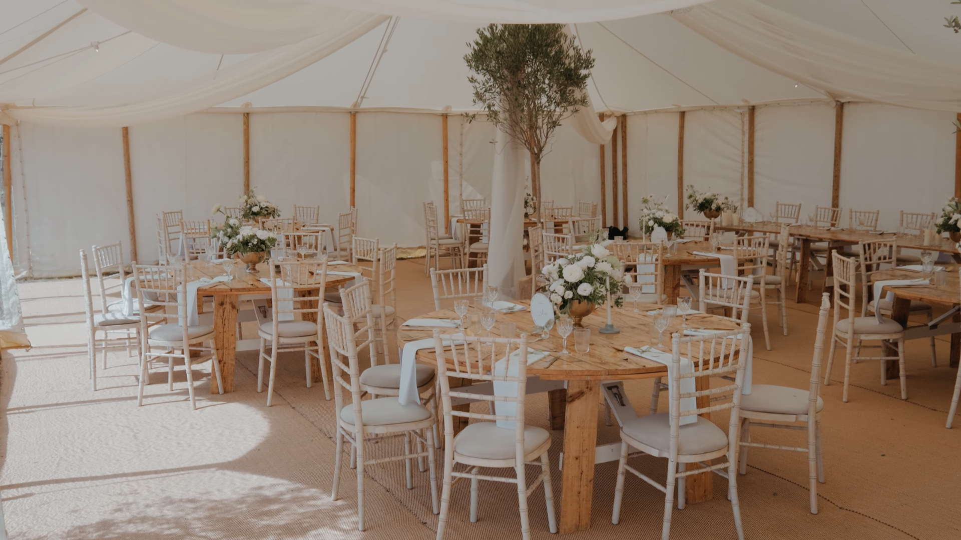 Marquee wedding breakfast at the Ark at Egwood with white florals, olive tree, chiffon drapes and chandelier