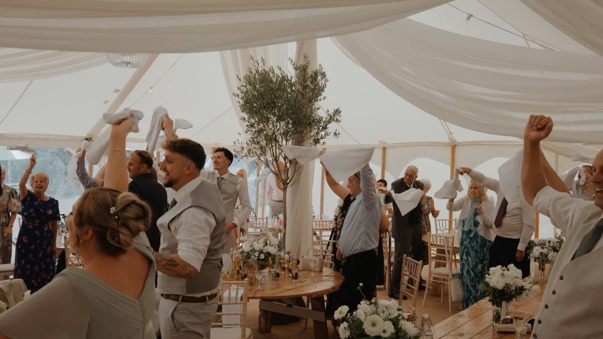 Guests waving napkins in celebration inside the marquee at Aimee and Luke's Ark at Egwood wedding